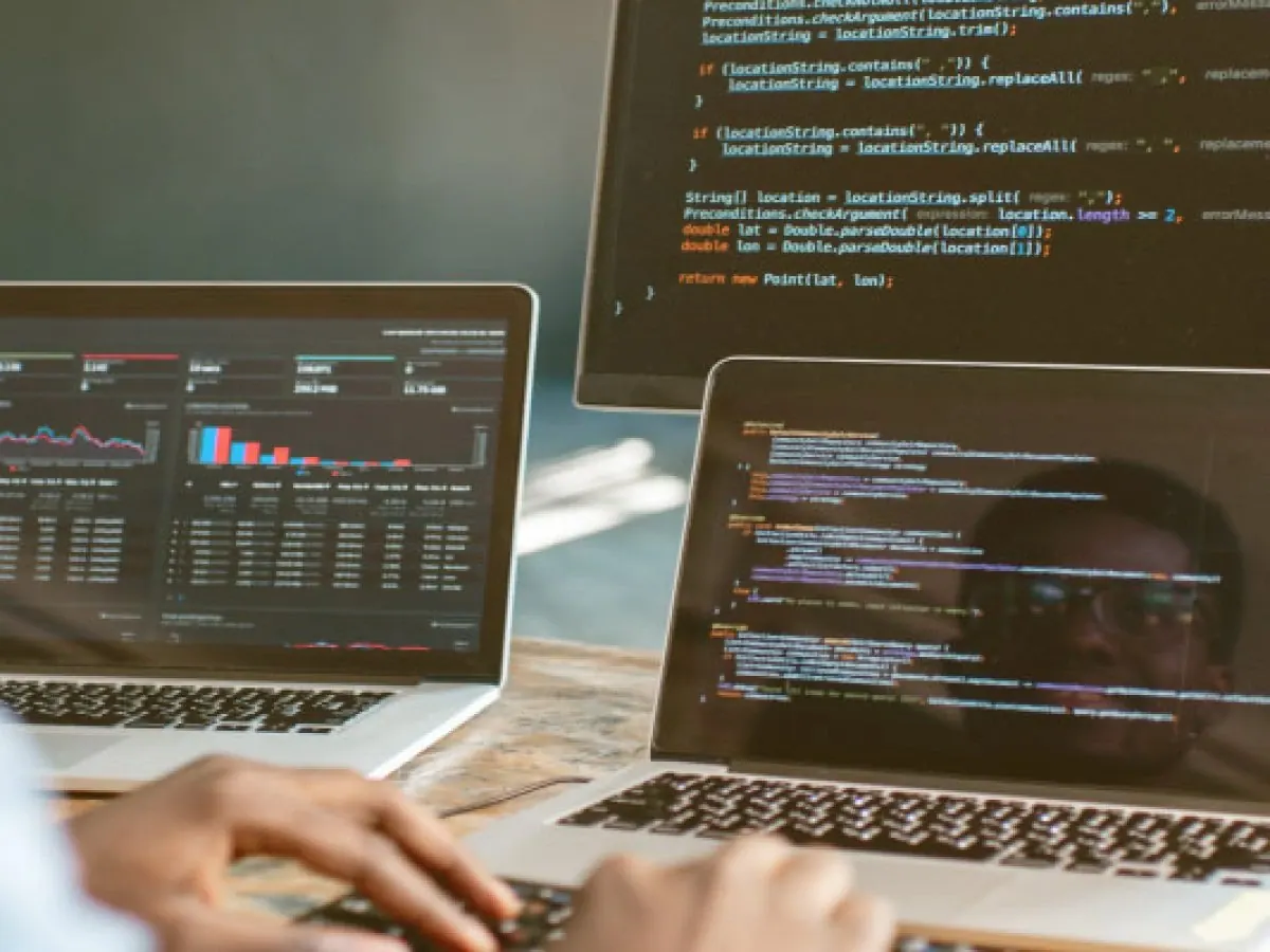 Deux ordinateurs portables affichant du code et un tableau de bord de données