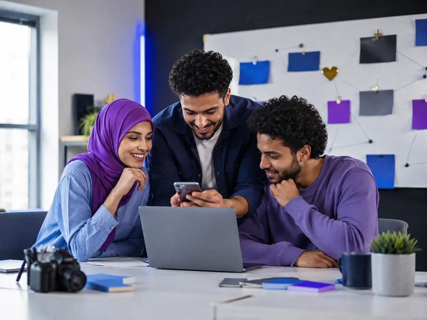 Trois jeunes professionnels consultent un smartphone et un ordinateur portable